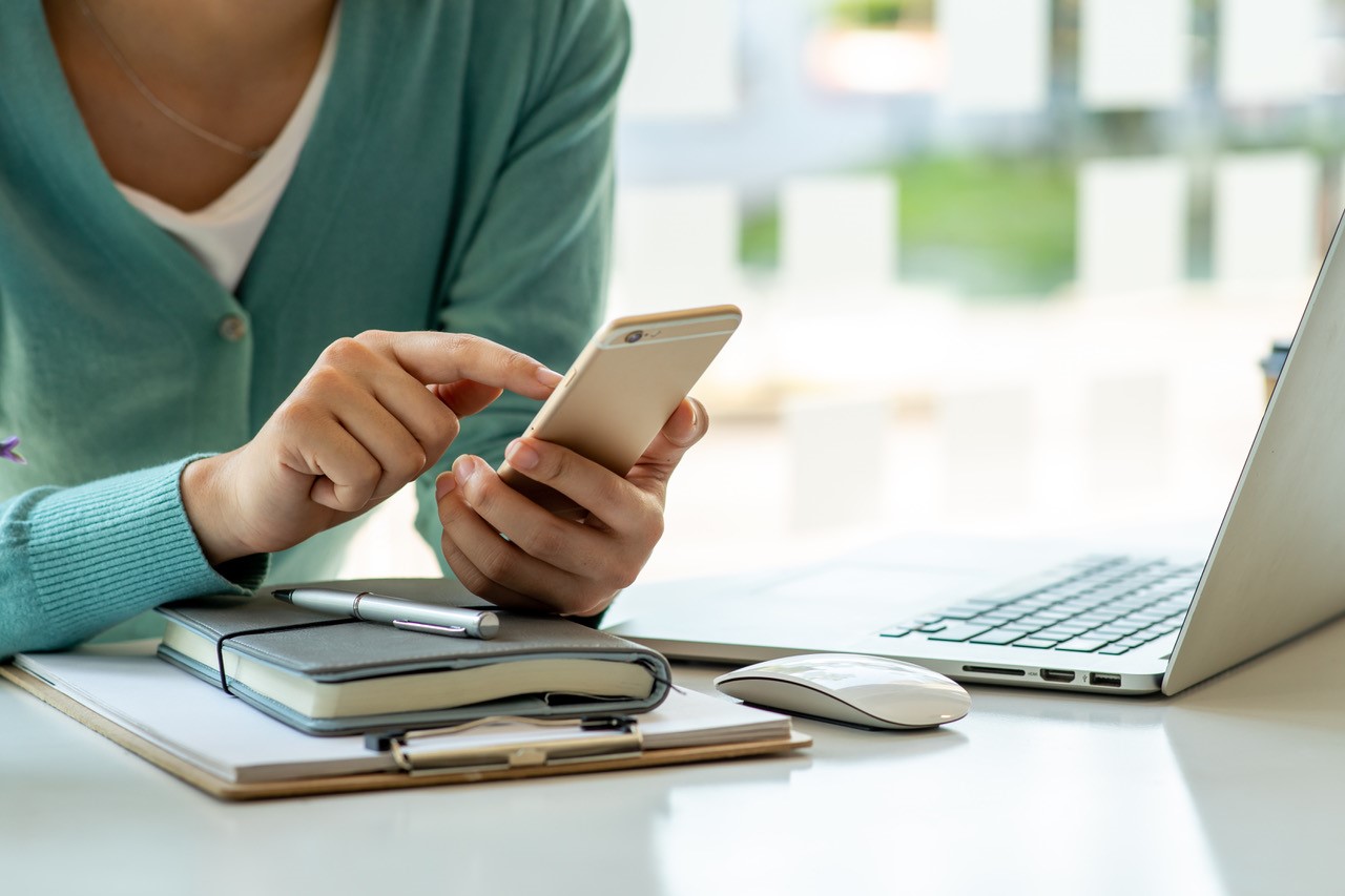 Women next to a laptop on a mobile phone